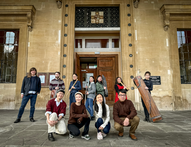 A group of 10 musicans: 4 kneeling in front of 6 holding instrumnts in front o the main entrance the Department of Music,Victoria Rooms